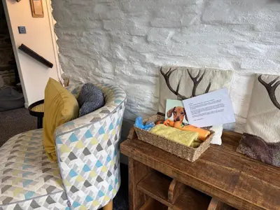 a living room with a couch and a table with a chair at Horseshoe Cottage in Looe
