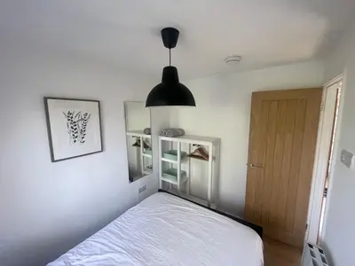 a bedroom with a bed and a black lamp at Woodland bungalow, fantastic location in Uny Lelant