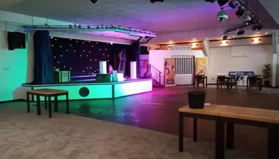 a room with a stage with tables and purple lights at Woodland bungalow, fantastic location in Uny Lelant