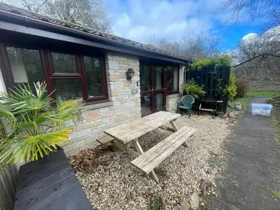 a wooden picnic table in front of a building at Woodland bungalow, fantastic location in Uny Lelant