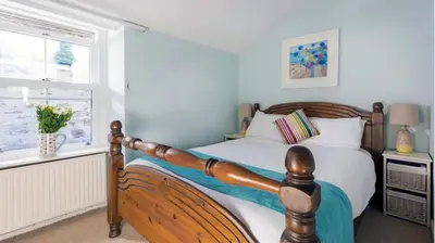 a bedroom with a wooden bed and a window at St Ives fisherman cottage, Sleeps 5, pet friendly in St Ives