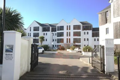a building with a gate in front of a parking lot at Headland View at Bredon Court in Newquay