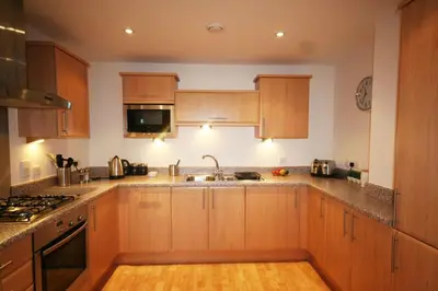 a kitchen with wooden cabinets and a sink at Headland View at Bredon Court in Newquay