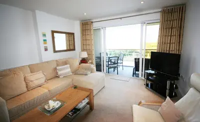 a living room with a couch and a table at Headland View at Bredon Court in Newquay