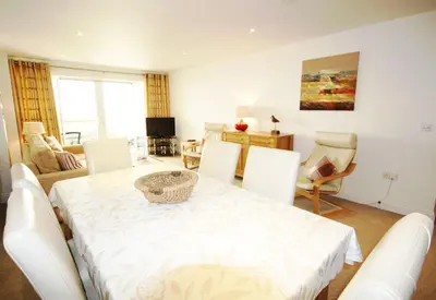 a living room with a white table and chairs at Headland View at Bredon Court in Newquay