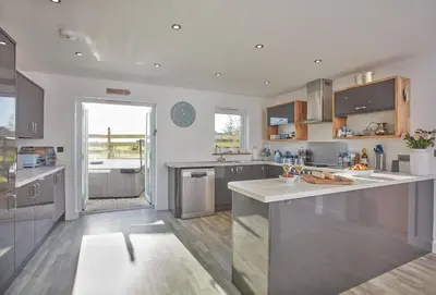 a large kitchen with stainless steel appliances and a large window at Little Treveth Lowen in Saint Minver