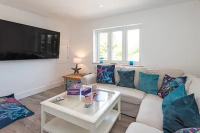 a living room with a couch and a tv at Little Treveth Lowen in Saint Minver