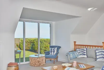a living room with a couch and a window at Little Treveth Lowen in Saint Minver