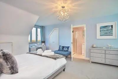 a bedroom with a bed and a chandelier at Little Treveth Lowen in Saint Minver