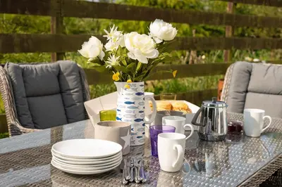 a table with plates and a vase of white flowers at Little Treveth Lowen in Saint Minver