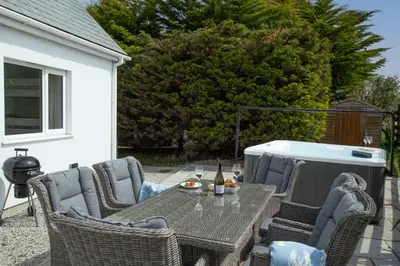 a patio with a table and chairs and a heater at Little Treveth Lowen in Saint Minver