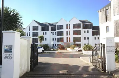 a building with a gate in front of a parking lot at Surf's Up! in Newquay