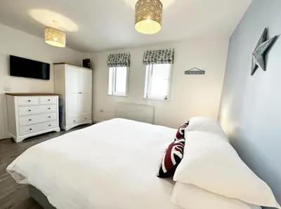 a bedroom with a white bed and a tv at Surf's Up! in Newquay