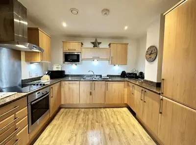 a large kitchen with wooden cabinets and a sink at Surf's Up! in Newquay