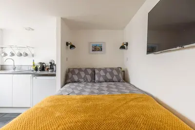 a bedroom with a bed with a yellow blanket at Sea Whispers at Porthleven in Porthleven