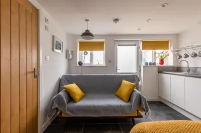a living room with a couch with two yellow pillows at Sea Whispers at Porthleven in Porthleven