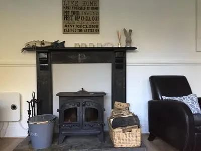 a living room with a fireplace and a chair at Hollyhocks in Saint Minver