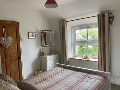 a bedroom with a bed and a window at Hollyhocks in Saint Minver