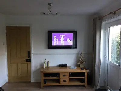a living room with a tv on the wall at Hollyhocks in Saint Minver
