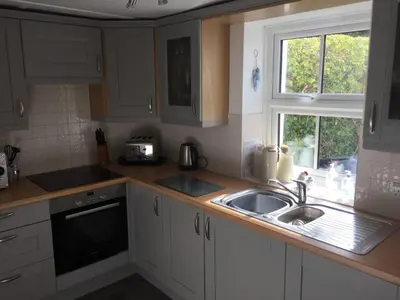 a kitchen with white cabinets and a sink and a window at Hollyhocks in Saint Minver