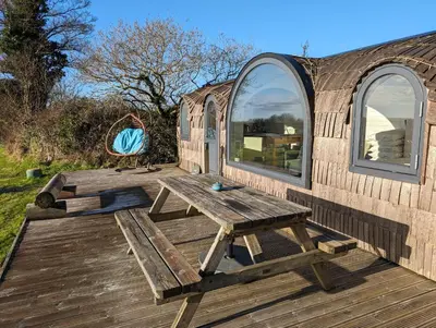 a wooden picnic table on a wooden deck in a yurt at Jam First - Lydcott Glamping, Cornish Sea Views in East Looe