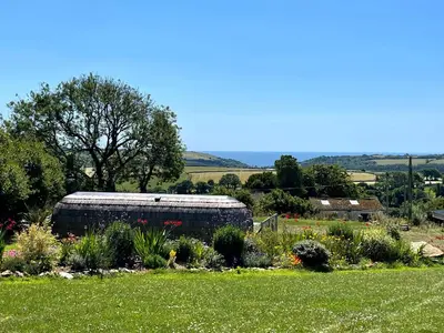a garden with a building in the middle of a field at Jam First - Lydcott Glamping, Cornish Sea Views in East Looe