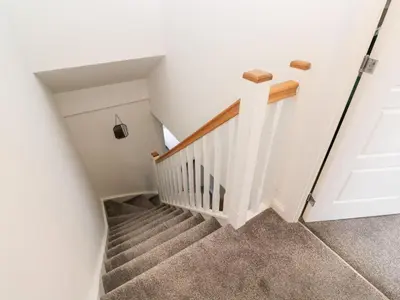 a staircase in a home with white walls and carpet at 20 Bishops Way in Falmouth