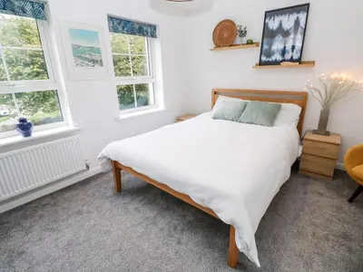 a bedroom with a bed and two windows at 20 Bishops Way in Falmouth