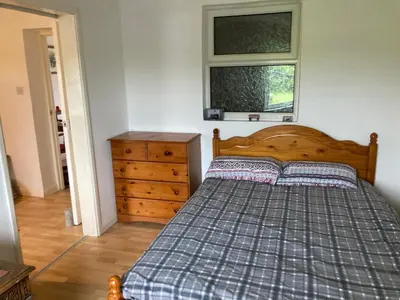 a bedroom with a bed and a dresser and a window at Little Haven in Launceston