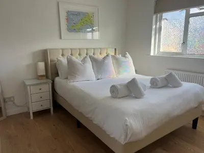 a bed with white pillows and a window at Family Home with Sauna & Garden in Newquay