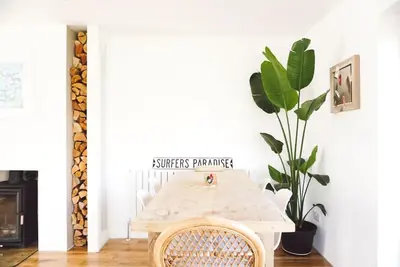 a white dining room with a table and a plant at Family Home with Sauna & Garden in Newquay