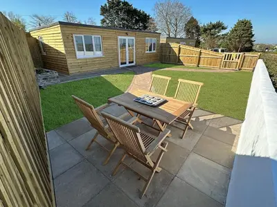a patio with a table and chairs in a yard at Citrus Chalet, modern light and airy! in Redruth
