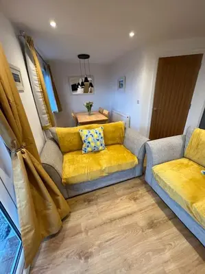 a living room with two couches and a table at Citrus Chalet, modern light and airy! in Redruth