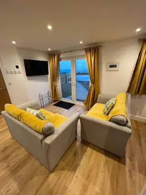 a living room with two couches with yellow cushions at Citrus Chalet, modern light and airy! in Redruth
