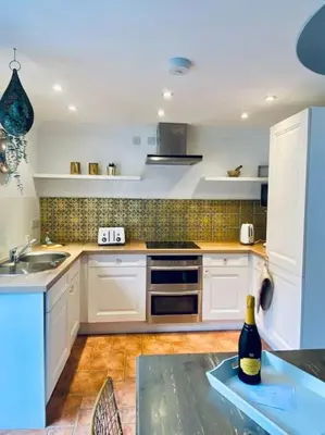 a kitchen with white cabinets and a bottle of wine on a table at Charlestown Cottage Harbour & Beach short walk! in Charlestown