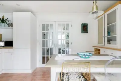 a kitchen with white cabinets and a table and chairs at Charlestown Cottage Harbour & Beach short walk! in Charlestown