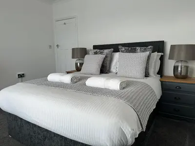 a bedroom with a large white bed with pillows at Porth View Newquay in Saint Columb Minor