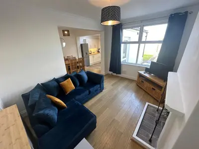 a living room with a blue couch and a television at Porth View Newquay in Saint Columb Minor