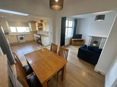 a kitchen and living room with a table and a couch at Porth View Newquay in Saint Columb Minor