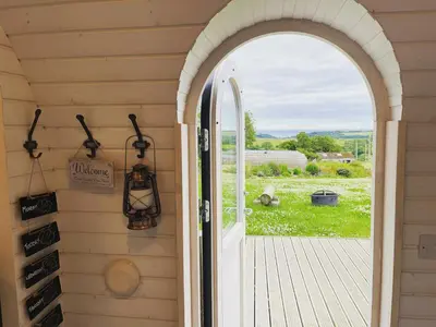an arched door leading to a porch with a view at Clotted Cream -Lydcott Glamping, Cornish Sea Views in Looe