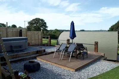a patio with a table and chairs and an umbrella at Secluded Luxury Pod with Hot Tub in Launceston