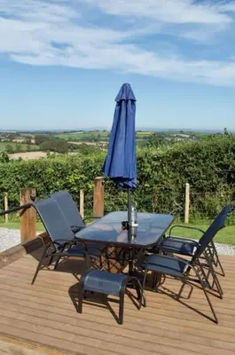 a table and chairs with an umbrella on a deck at Secluded Luxury Pod with Hot Tub in Launceston