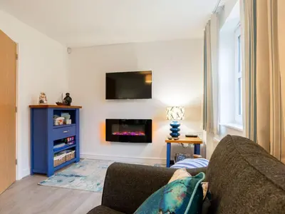 a living room with a couch and a tv on a wall at Holiday Home Marshmallow House by Interhome in St Austell