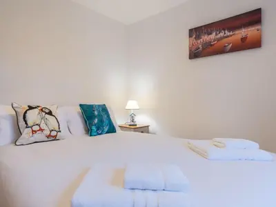 a bedroom with a white bed with towels on it at Holiday Home Marshmallow House by Interhome in St Austell