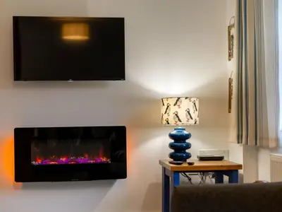 a living room with a fireplace and a tv on the wall at Holiday Home Marshmallow House by Interhome in St Austell