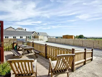 a patio with benches and a table and a fence at Holiday Home Francis Bungalow by Interhome in Helston