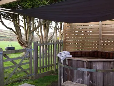 a hot tub in a fence with a black umbrella at Holiday Home Francis Bungalow by Interhome in Helston