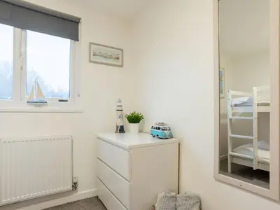 a bedroom with a mirror and a white dresser at Chalet Hot Tub Lodge 1 by Interhome in Helston