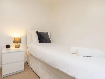 a bedroom with two white beds and a night stand at Chalet Hot Tub Lodge 2 by Interhome in Helston