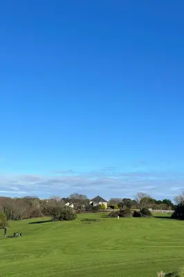 a view of a golf course with a green field at Chalet Hot Tub Lodge 2 by Interhome in Helston